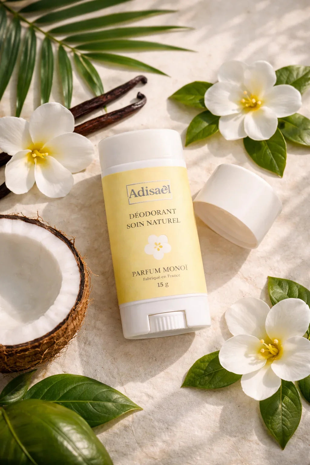Déodorant soin naturel parfum monoï sur fond tropical avec fleurs de tiaré, noix de coco et feuilles.